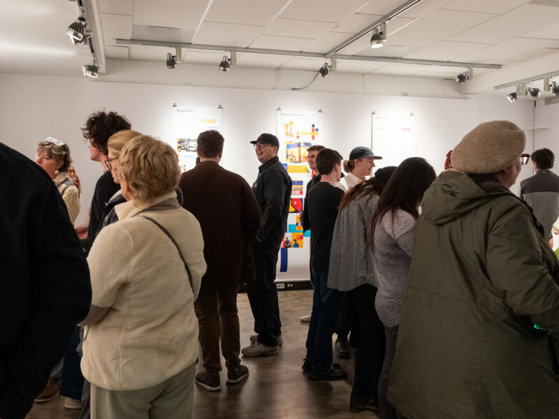 people gathering in the art gallery talking and looking at art on the walls