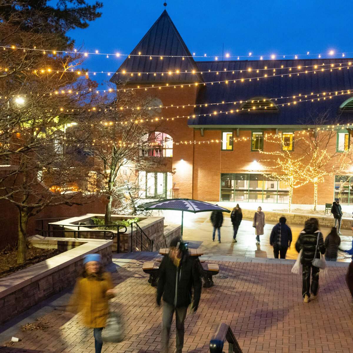 Christmas lights hanging over campus courtyard while students walk to class