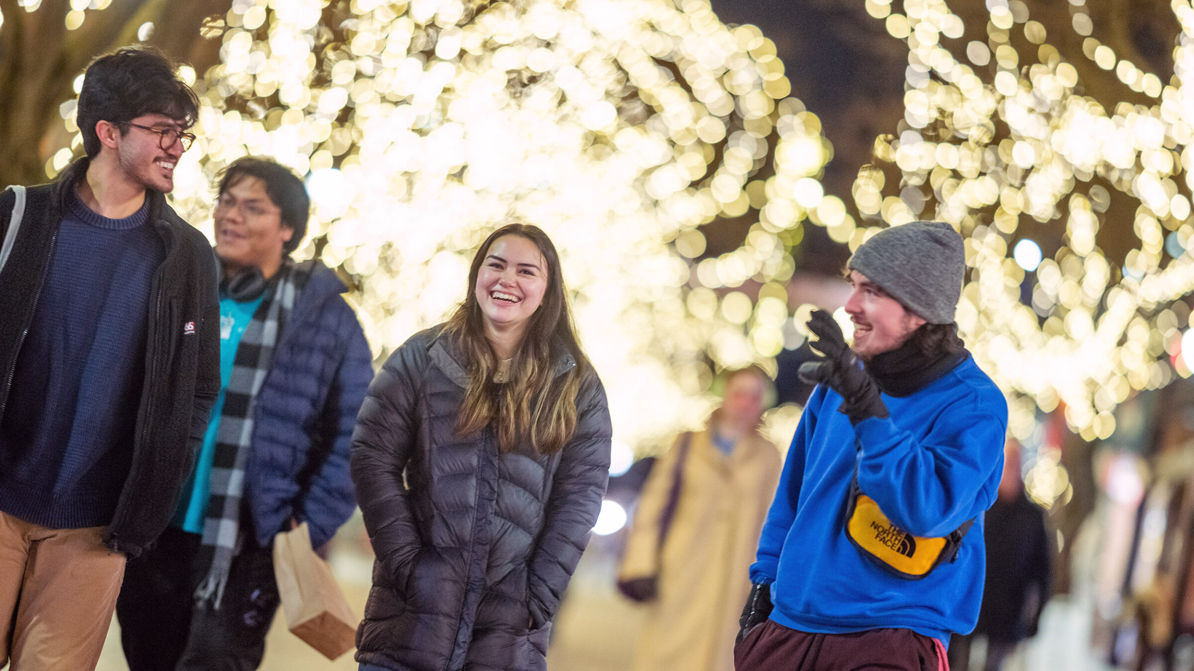 Students walking down Church Street in the winter, talking under Christmas lights