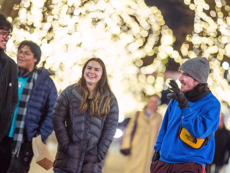 Students walking down Church Street in the winter, talking under Christmas lights