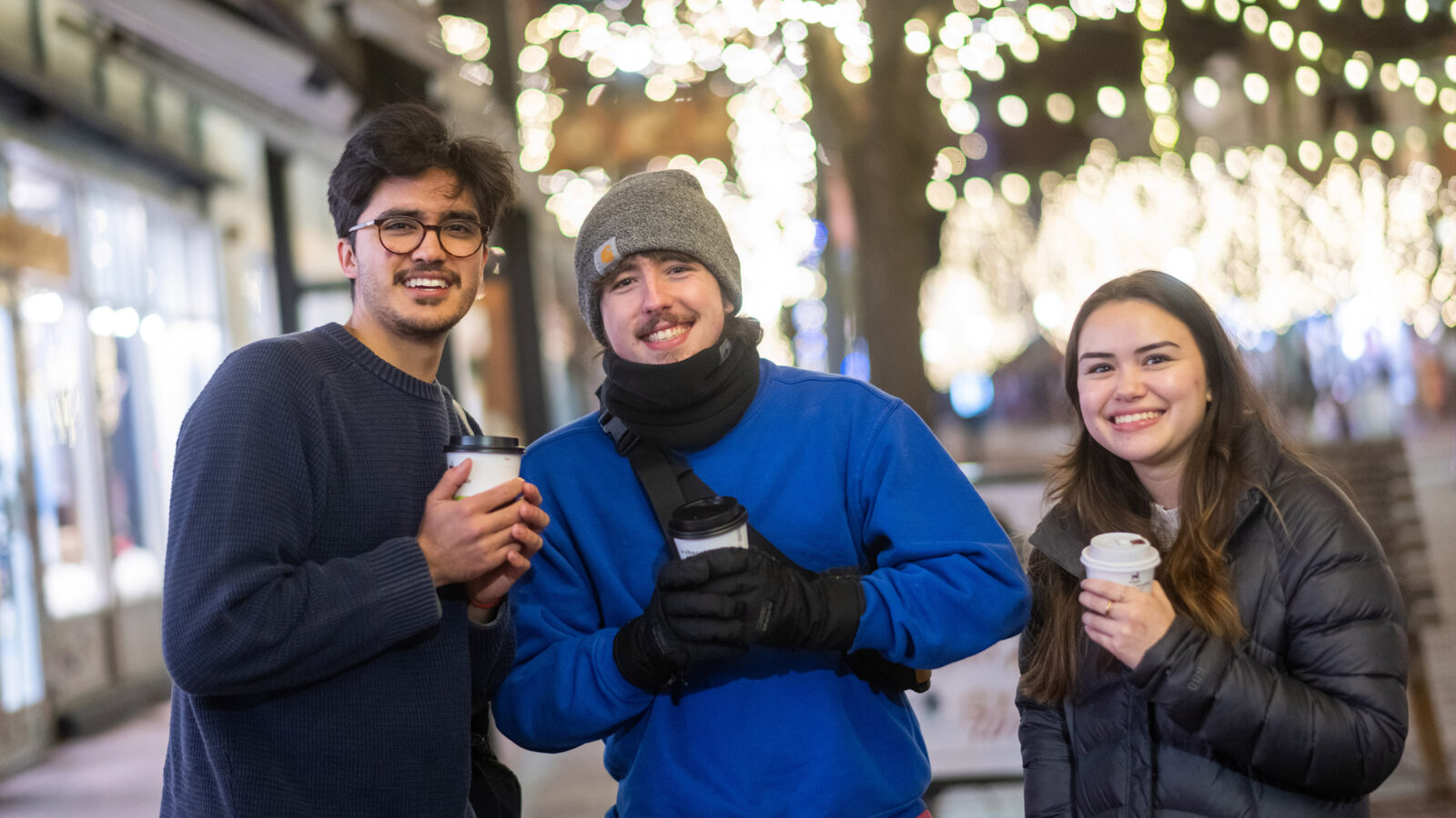 Students posing for a photo holding cups of coffee, smiling on Church Street