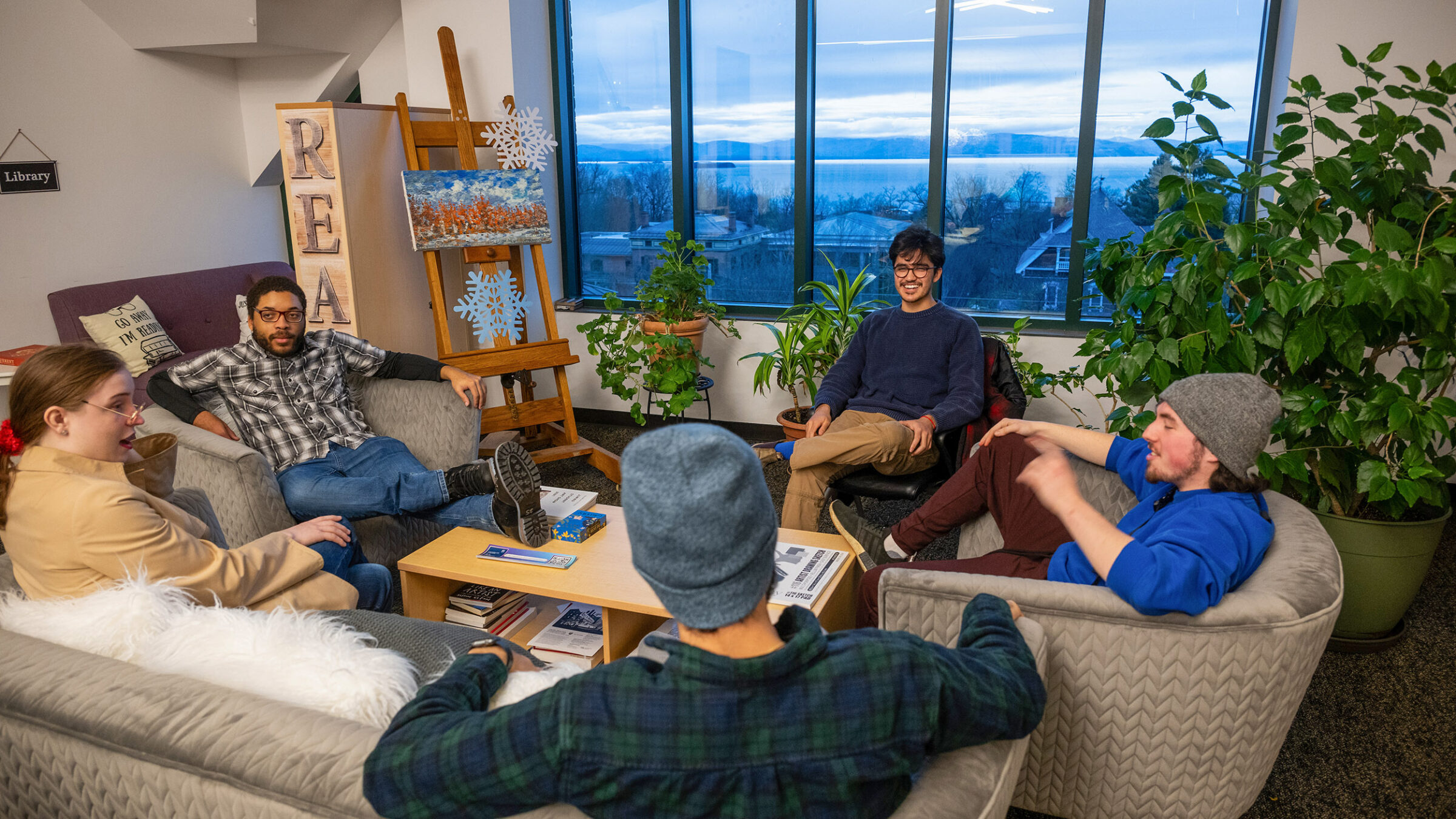 A group of students gathered around a table in front of a winter window on campus