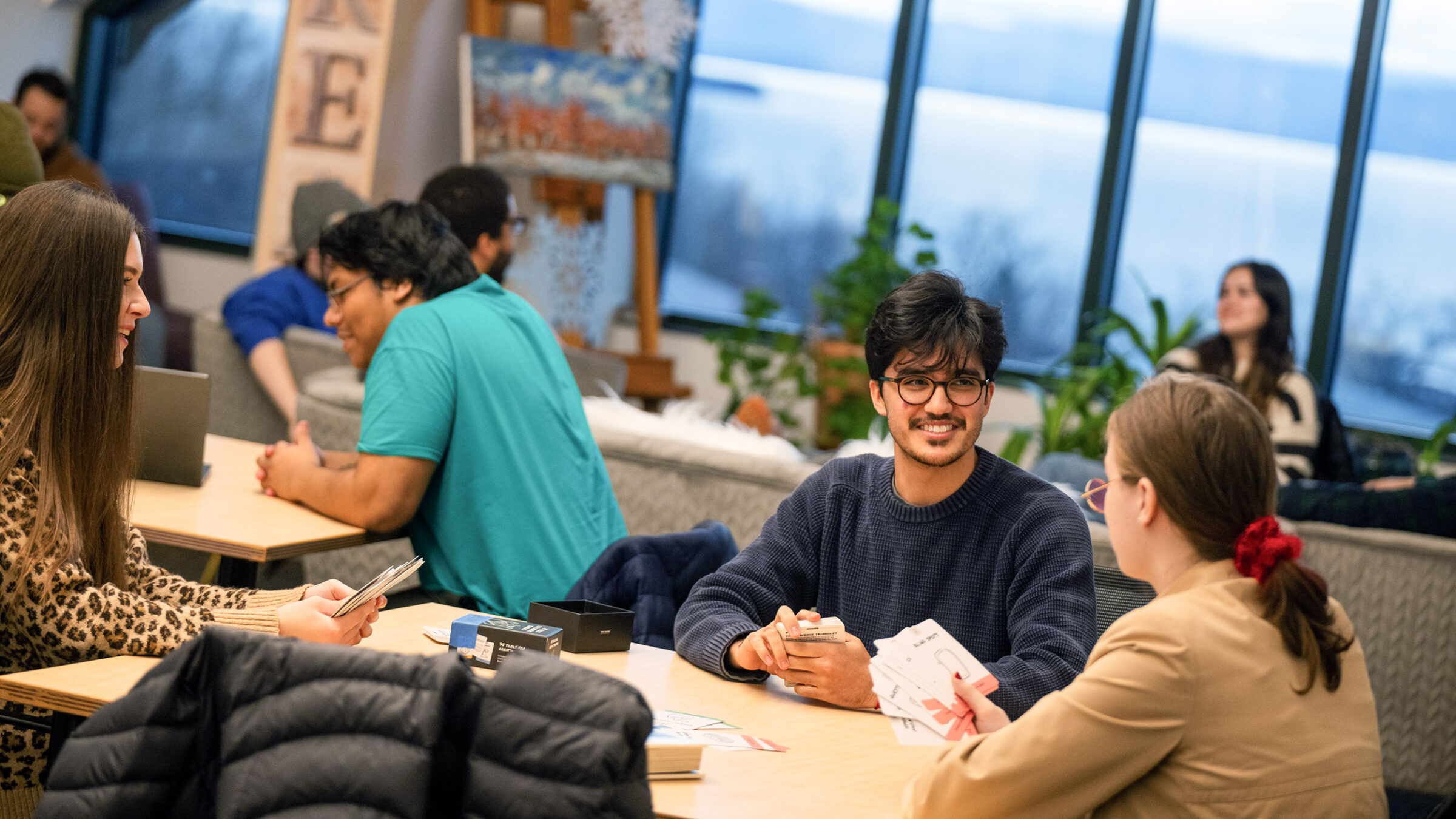 Students sitting on campus playing with cards and working on projects during the winter.