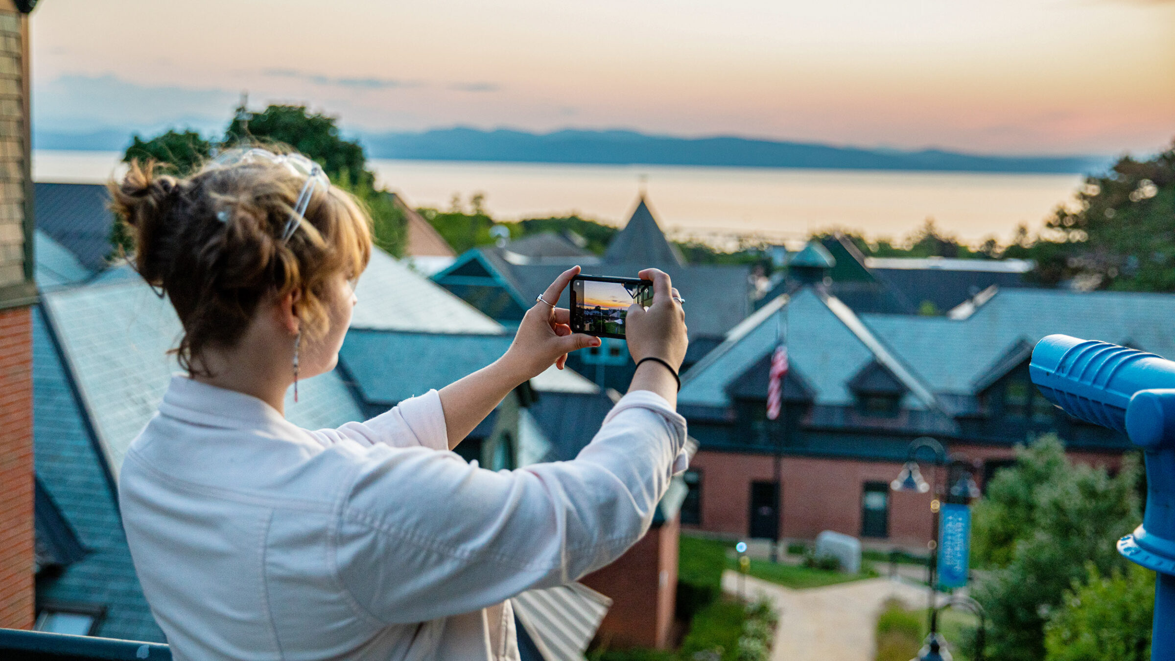 student taking a photo of the lake from the library balcony