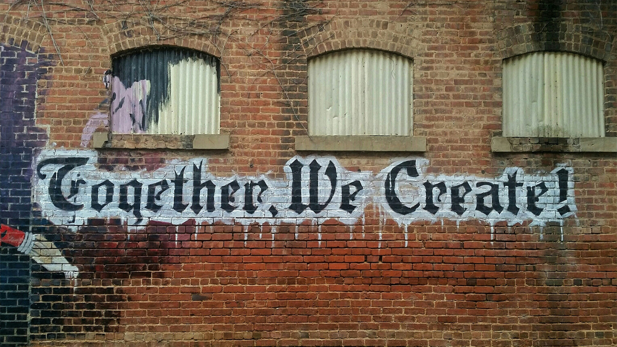 "together we create" painted on brick wall