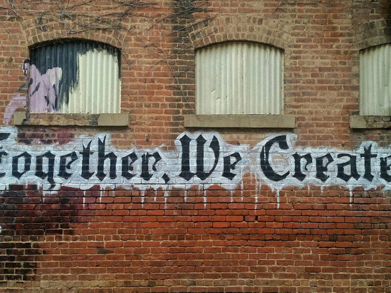 "together we create" painted on brick wall