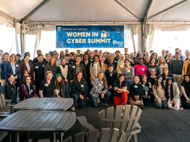 big group of people under a sign that reads "women in cyber summit"