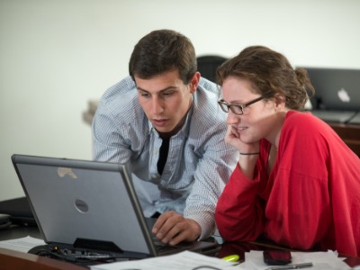 Students at Champlain College sitting shoulder to shoulder, sharing a laptop computer